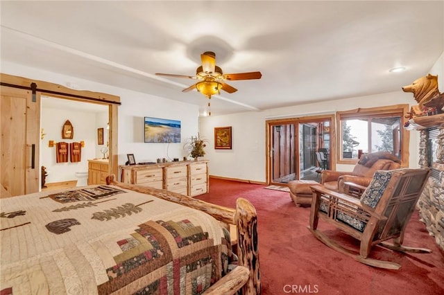 bedroom with ensuite bathroom, a barn door, a ceiling fan, access to exterior, and carpet