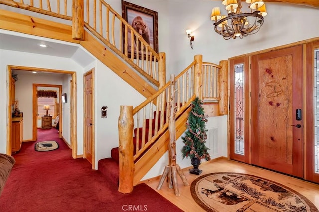 entrance foyer featuring carpet floors, stairway, a towering ceiling, and an inviting chandelier