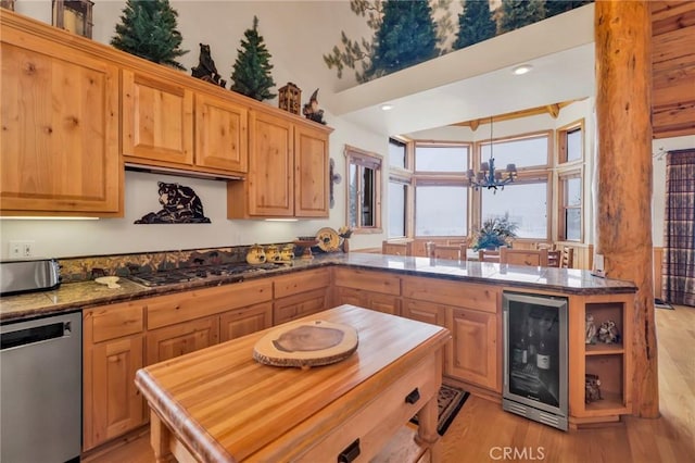 kitchen with light wood finished floors, beverage cooler, a peninsula, an inviting chandelier, and stainless steel appliances