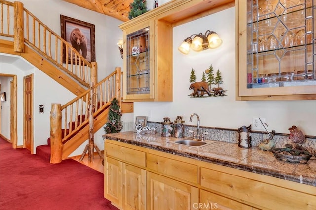 kitchen with tile counters, dark colored carpet, light brown cabinets, and a sink