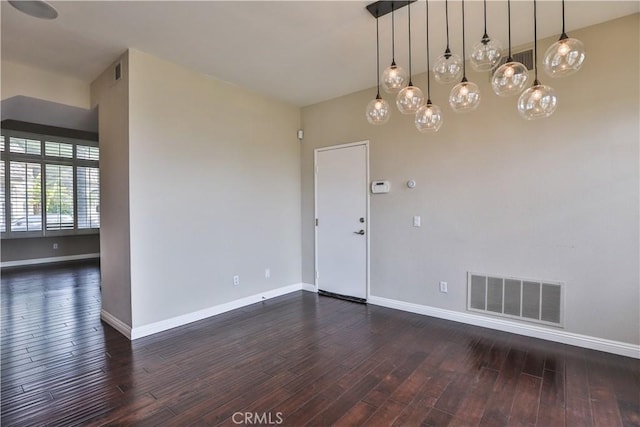 spare room with visible vents, baseboards, and dark wood-style flooring