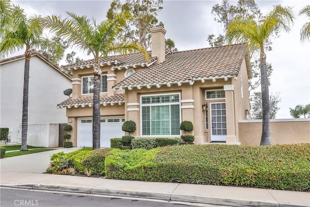 mediterranean / spanish-style home featuring stucco siding, driveway, a tile roof, a garage, and a chimney