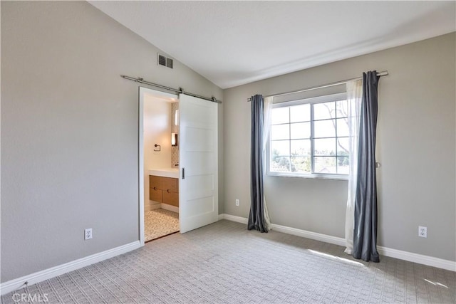 carpeted empty room featuring baseboards, visible vents, a barn door, and lofted ceiling