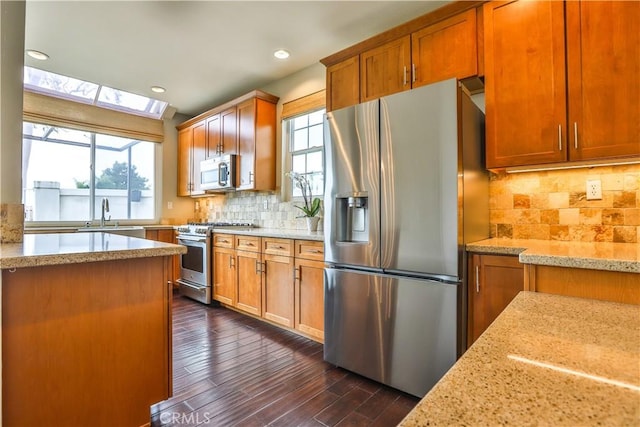 kitchen featuring a sink, light stone countertops, plenty of natural light, and appliances with stainless steel finishes