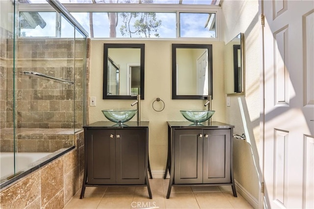 full bath with tile patterned flooring, two vanities, baseboards, and a sink