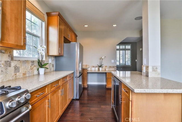 kitchen featuring light stone counters, appliances with stainless steel finishes, tasteful backsplash, and beverage cooler