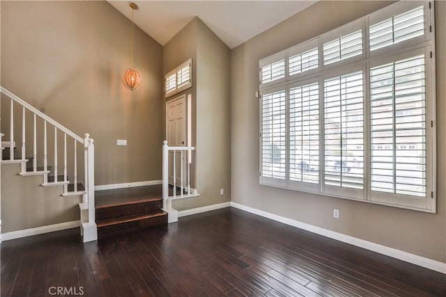 foyer entrance with hardwood / wood-style floors, vaulted ceiling, stairway, and baseboards