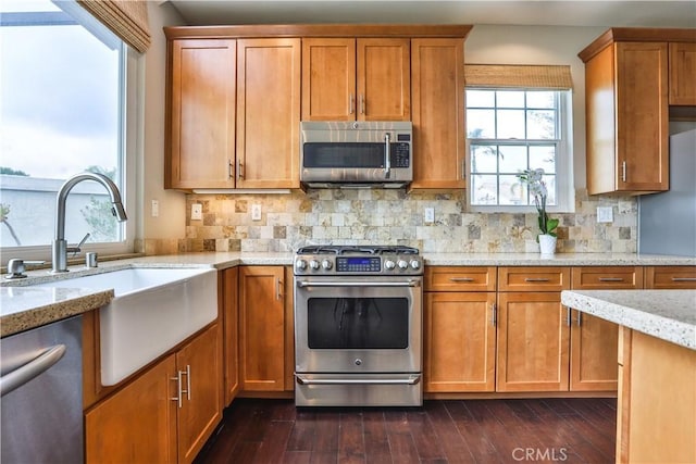 kitchen with a sink, tasteful backsplash, dark wood finished floors, stainless steel appliances, and brown cabinetry