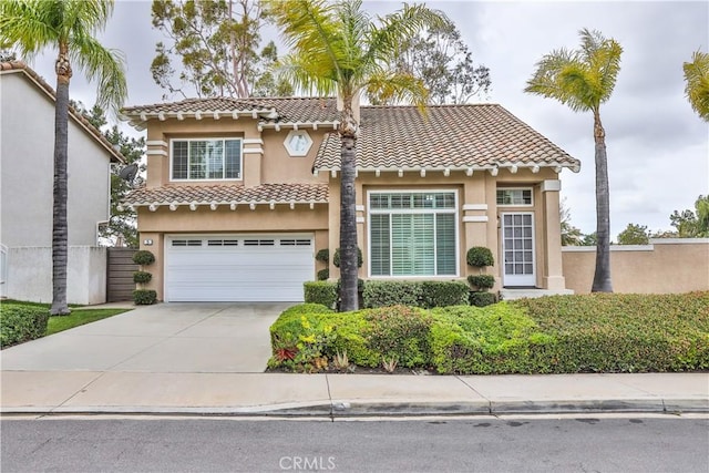 mediterranean / spanish house with stucco siding, driveway, a tile roof, and an attached garage