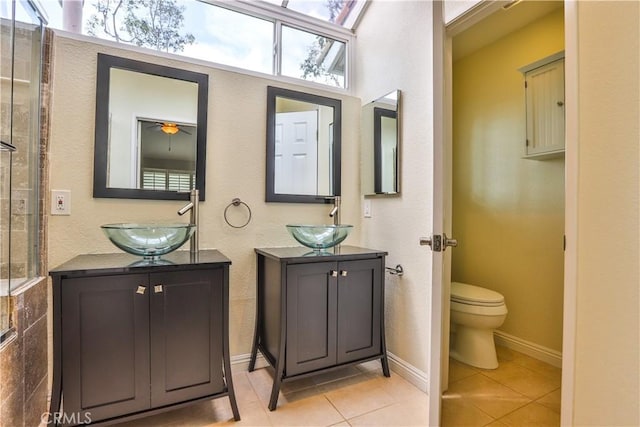 bathroom with tile patterned flooring, two vanities, toilet, and a sink