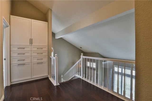 interior space featuring lofted ceiling with beams, an upstairs landing, and dark wood-style floors