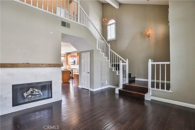 unfurnished living room featuring stairs, visible vents, baseboards, and dark wood-style flooring