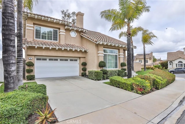 mediterranean / spanish home featuring a chimney, stucco siding, concrete driveway, a garage, and a tile roof