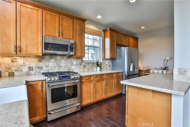 kitchen with brown cabinets, backsplash, stainless steel appliances, light stone countertops, and dark wood-style flooring