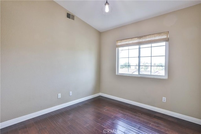 empty room featuring visible vents, baseboards, lofted ceiling, and dark wood-style flooring