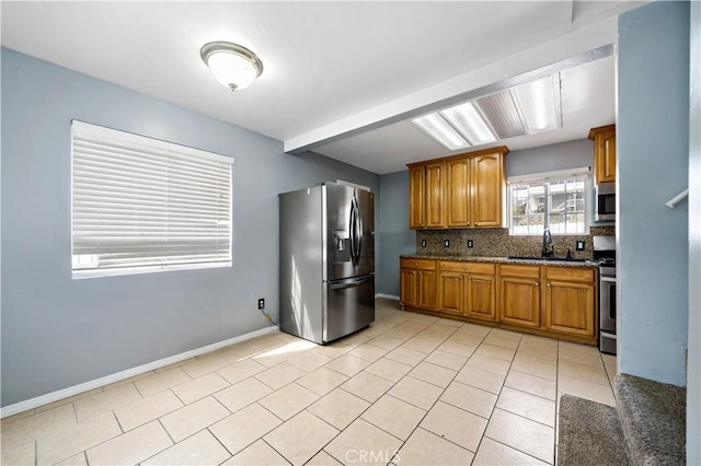 kitchen featuring light tile patterned floors, stainless steel appliances, baseboards, tasteful backsplash, and brown cabinetry