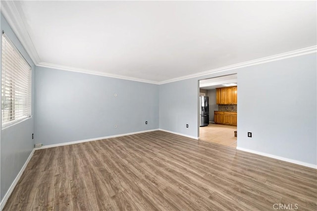 unfurnished living room featuring light wood finished floors, baseboards, and crown molding