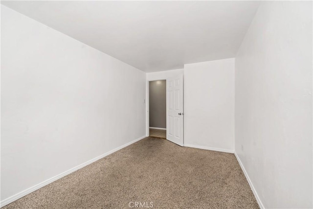 empty room featuring carpet flooring and baseboards