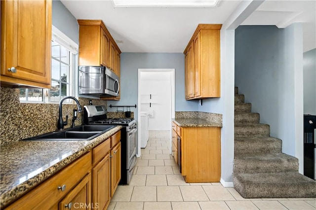 kitchen featuring brown cabinets, appliances with stainless steel finishes, backsplash, and a sink