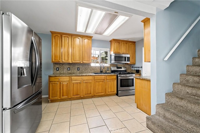 kitchen with decorative backsplash, light stone counters, stainless steel appliances, and a sink