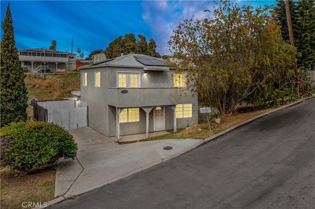 view of front of house featuring solar panels, fence, and stucco siding