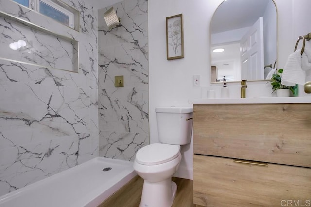 full bath featuring toilet, a marble finish shower, and vanity