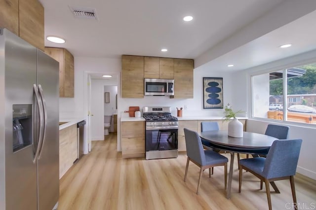 kitchen featuring stainless steel appliances, light wood-type flooring, light countertops, and visible vents