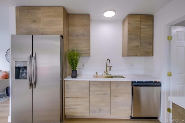 kitchen featuring a sink, light countertops, appliances with stainless steel finishes, light brown cabinetry, and modern cabinets