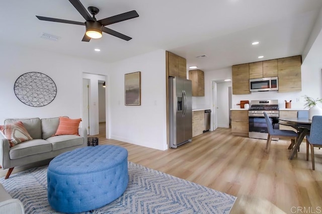 living room with baseboards, visible vents, a ceiling fan, light wood-style floors, and recessed lighting