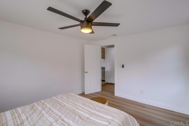 unfurnished bedroom featuring a ceiling fan, visible vents, baseboards, and wood finished floors