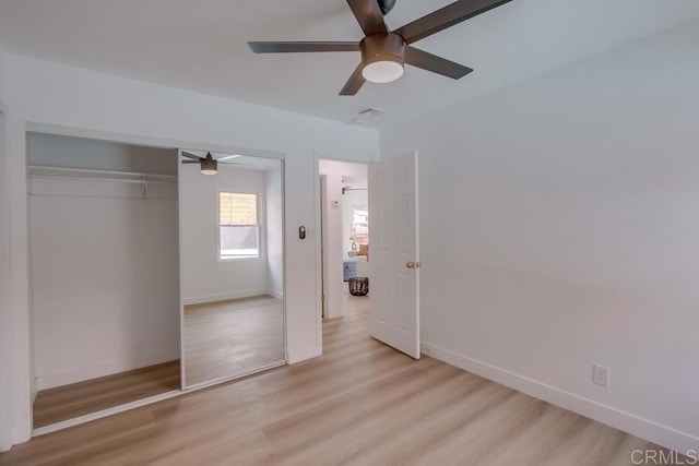 unfurnished bedroom with ceiling fan, a closet, light wood-style flooring, and baseboards