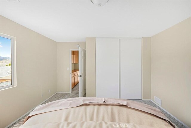 unfurnished bedroom featuring baseboards, visible vents, carpet floors, and a closet