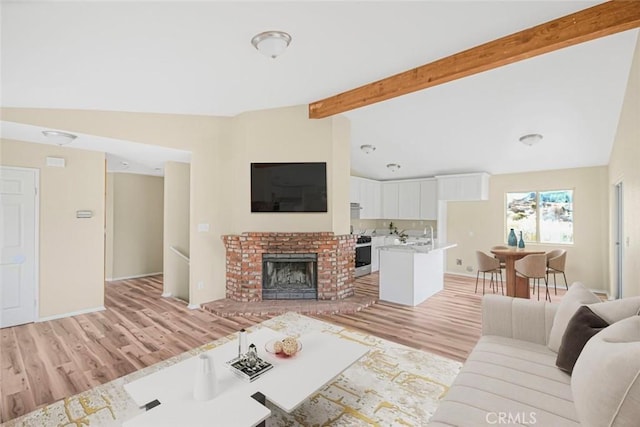 living area featuring a brick fireplace, vaulted ceiling with beams, baseboards, and light wood-type flooring