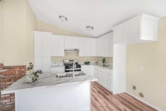 kitchen with under cabinet range hood, vaulted ceiling, light stone counters, light wood-style flooring, and stainless steel gas range