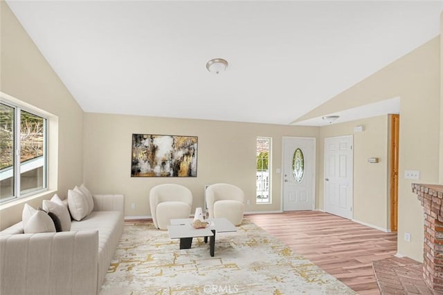 living area featuring lofted ceiling, a healthy amount of sunlight, and light wood-type flooring