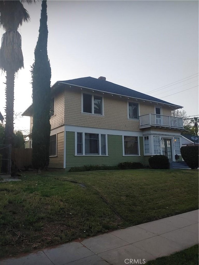 view of front of house with a balcony and a front lawn