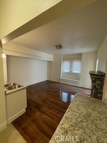 interior space featuring a stone fireplace, baseboards, and wood finished floors