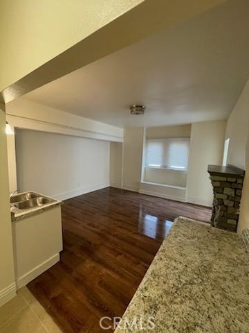 interior space featuring a stone fireplace, baseboards, and wood finished floors