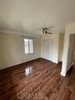 interior space with a ceiling fan, wood finished floors, baseboards, ornamental molding, and a closet