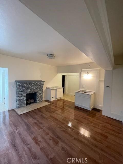 unfurnished living room with baseboards, wood finished floors, and a fireplace