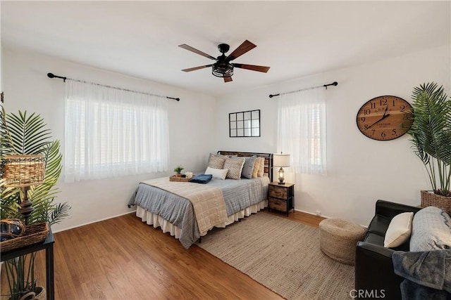 bedroom featuring multiple windows, wood finished floors, and a ceiling fan