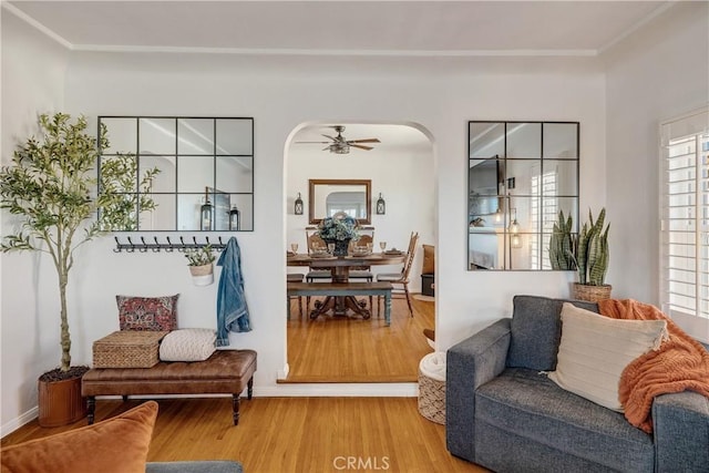 living area featuring arched walkways, ceiling fan, and wood finished floors