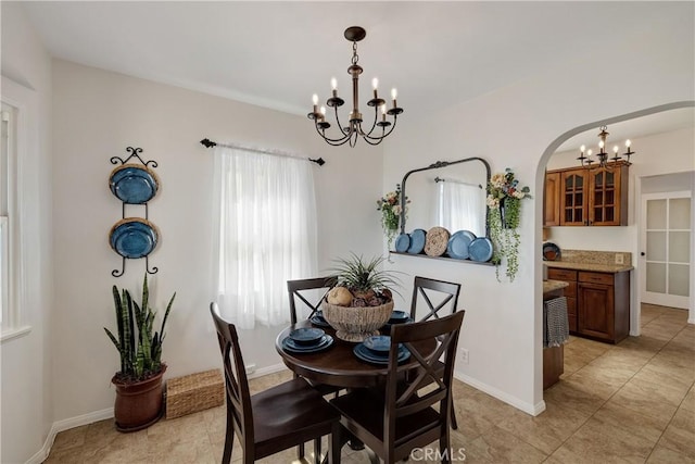 dining area with a chandelier, arched walkways, and baseboards