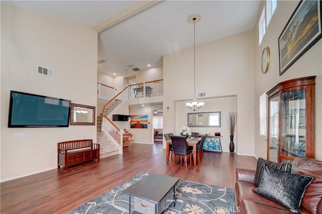 living room with visible vents, an inviting chandelier, wood finished floors, and stairway