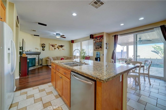 kitchen featuring visible vents, a fireplace, a sink, white fridge with ice dispenser, and dishwasher