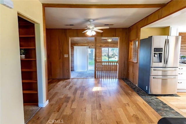 kitchen featuring wood walls, stainless steel refrigerator with ice dispenser, wood finished floors, and visible vents