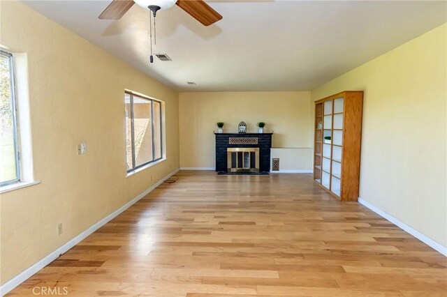 unfurnished living room with a healthy amount of sunlight, light wood-style floors, a fireplace, and visible vents