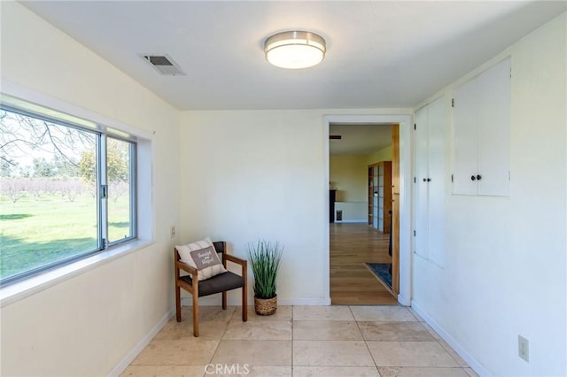 corridor featuring light tile patterned flooring, visible vents, and baseboards