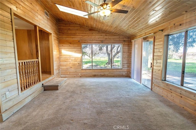 unfurnished living room with lofted ceiling with skylight, wood ceiling, carpet floors, and wooden walls