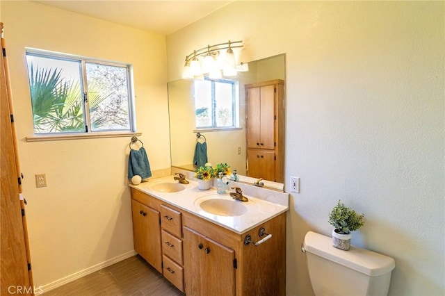 bathroom featuring double vanity, a sink, toilet, and wood finished floors